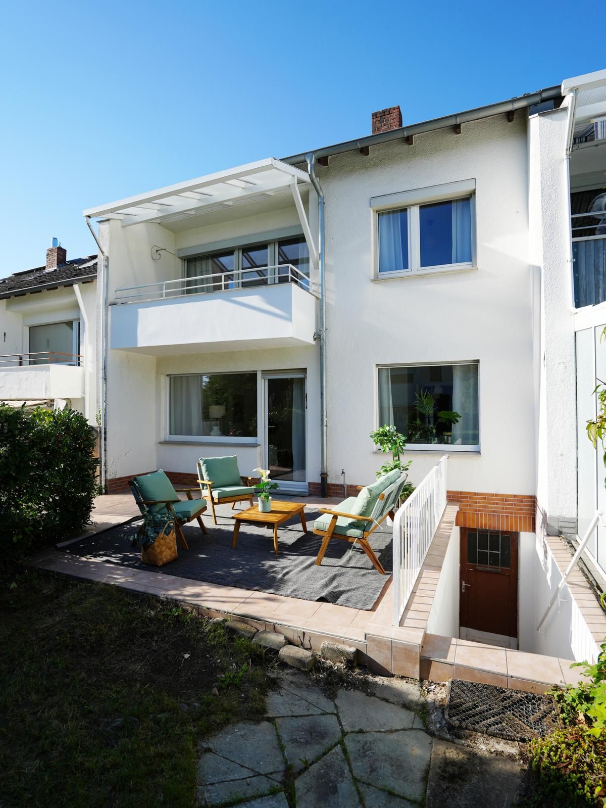 Rückansicht des Reihenhauses mit Terrasse, Garten und überdachtem Balkon im Obergeschoss